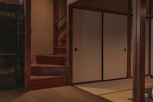 an open glass door in a room with stairs at CraftFlat Asakusa House in Tokyo