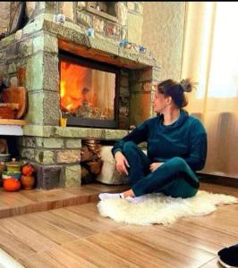 a woman sitting on the floor in front of a fireplace at Cazare Haiducita Bran in Zărneşti