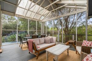 a screened porch with a couch and tables and windows at Seaside Sanctuary in Saint Leonards