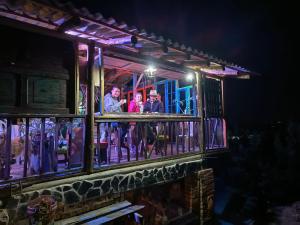 a group of people standing on the balcony of a house at night at Hotel Rural Granja Agroecoturistica Santa Barbara in Simijaca