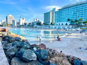 une plage avec des gens dans l'eau et dans les bâtiments dans l'établissement Condado Beachfront Tantra Apartment, à San Juan