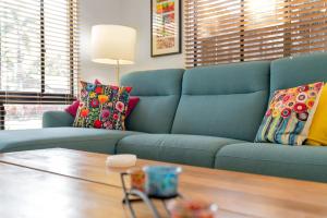 a blue couch with colorful pillows in a living room at 3-Bed Family Home with Pool & BBQ by the Beach in Clifton Beach