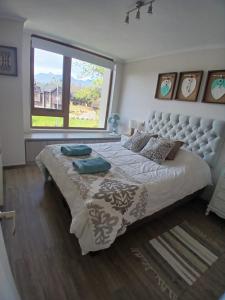 a bedroom with a large bed with a large window at CONDOMINIO LOS CASTAÑOS ALICURA, PUCÓN, departamento 2 dormitorios, 1 baño, estacionamiento, piscina in Pucón