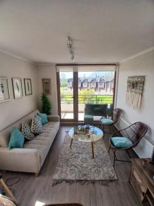 a living room with a couch and a table at CONDOMINIO LOS CASTAÑOS ALICURA, PUCÓN, departamento 2 dormitorios, 1 baño, estacionamiento, piscina in Pucón
