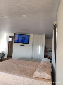 a bedroom with a bed with a tv on the wall at Chalé CIO DA TERRA in Alto Paraíso de Goiás