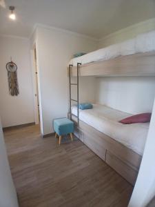 a bedroom with two bunk beds and a blue stool at CONDOMINIO LOS CASTAÑOS ALICURA, PUCÓN, departamento 2 dormitorios, 1 baño, estacionamiento, piscina in Pucón +11 photos