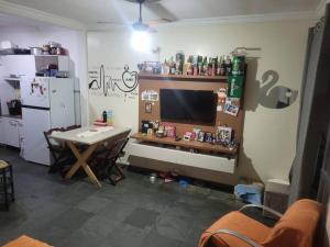 a living room with a table and a television and a kitchen at Casa Tomazella in Guarujá