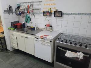 a small kitchen with a stove and a sink at Casa Tomazella in Guarujá +6 photos