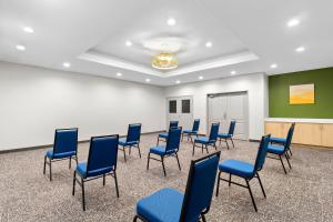 a waiting room with blue chairs and a wall at Spark By Hilton Missouri City in Missouri City