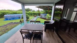 a table and chairs on a porch with a view of a garden at Arenal Nephelium Country Home, Refugio rural con piscina, jacuzzi y balcón con hermosas vistas al Volcán Arenal, en una finca privada in Fortuna