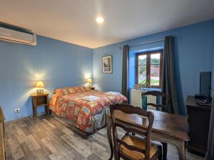 Un dormitorio con paredes azules y una cama y una mesa. en Charmante Chambre Myosotis avec Jardin et DVD - FR-1-589-665, en Rehaupal