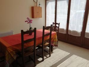 Una mesa de comedor con dos sillas y un jarrón con flores. en Charmante Chambre Myosotis avec Jardin et DVD - FR-1-589-665, en Rehaupal