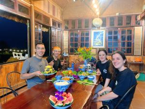 a group of people sitting around a table with food at SIM Farmstay in Ha Giang