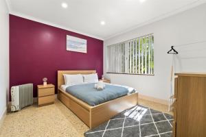 Un dormitorio con una cama y una pared morada. en River Tree Chalet - Margaret River NEW, en Margaret River Town