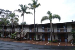 an exterior view of a hotel with palm trees at Kaloha Holiday Resort Phillip Island in Cowes