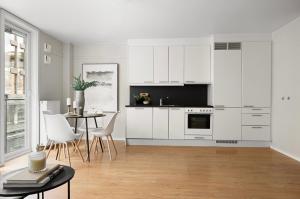 a kitchen with white cabinets and a table with chairs at Tjuvholmen - ved Aker Brygge in Oslo