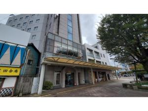 a tall white building with a tree in front of it at Nobeoka Urban-Hotel - Vacation STAY 30446v in Nobeoka