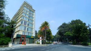 a tall building with a palm tree next to a street at Tebu Hotel Bandung in Bandung