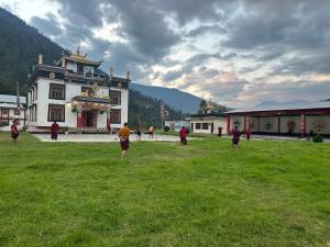 a group of people standing in a field in front of a building at Pema Dekey monastic guest house in Dirang Dzong