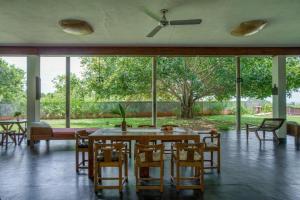 a dining room with a table and chairs and windows at Mango Hill Pondicherry in Puducherry