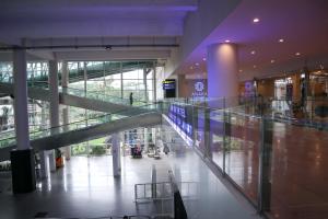 an empty mall hallway with escalators in a building at Anara Sky Kualanamu Hotel in Medan