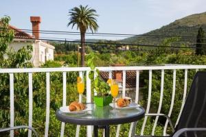 a table with bread and glasses of orange juice on a balcony at Villa Roza - Studio Apartment with Balcony in Mokošica