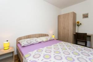 Schlafzimmer mit einem Bett mit lila Bettwäsche und Kissen in der Unterkunft Apartments Stipo - Two Bedroom Apartment with Balcony and Sea View A3 in Drače