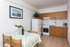 eine Küche mit einem Tisch und einem weißen Kühlschrank in der Unterkunft Apartments Stipo - Two Bedroom Apartment with Balcony and Sea View A3 in Drače + 8 Fotos