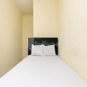 a bed with white pillows in a room at Pulogadung Residence by Nam RedPartner in Jakarta