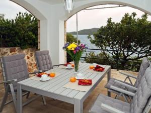 a table with a vase of flowers on a patio at Holiday Home Odiseja- One Bedroom Apartment with Terrace and Sea View in Brsečine