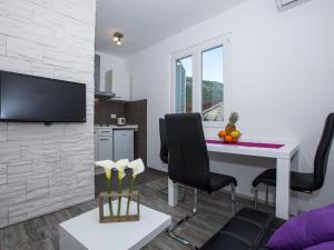 ein Wohnzimmer mit Tisch und Stühlen und einem Fernseher in der Unterkunft Villa Roza - One-Bedroom Apartment with Balcony in Mokošica