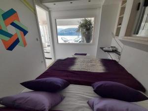 a bedroom with a bed with purple pillows and a window at Apartment OM - One Bedroom Apartment with Balcony and Sea view in Povlja