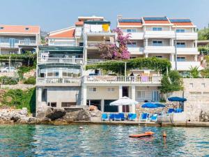 a building on the water with chairs and umbrellas at Apartments Ra ica Molunat - Basic Studio in Molunat