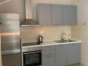 a kitchen with white cabinets and a sink and a stove at Apartments Nives - Three Bedroom Apartment with Terrace and Sea View in Smokvica