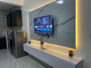 a kitchen with a counter with a tv on a wall at Lavender Cozy apartment in Namugongo