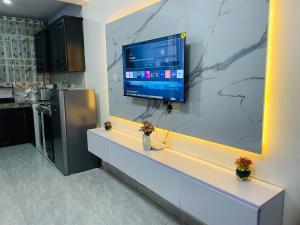 a kitchen with a large tv on a wall at Lavender Cozy apartment in Namugongo