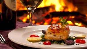 a plate with a piece of meat with vegetables and a glass of wine at PPH Living Bhimas in Tadas