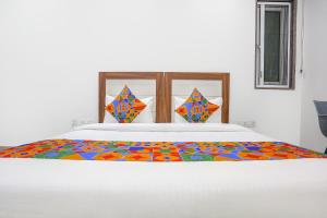 a white bed with a colorful comforter on it at FabHotel Aerosky - Nr Yashobhoomi Convention Centre in New Delhi