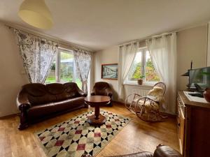 a living room with a leather couch and two windows at Dom Nadmorski "Casa Azul" Gdynia Kosakowo in Mechelinki