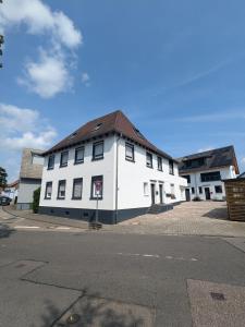 un bâtiment blanc avec un toit marron dans une rue dans l'établissement 55qm Messe Wohnung, Trade Fair, 6 Minuten zur Messe, à Rheinstetten