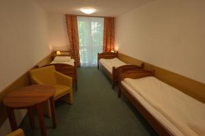 a room with three beds and a table and chairs at Pokoje Gościnne Białowieskiego Parku Narodowego, Białowieża in Białowieża