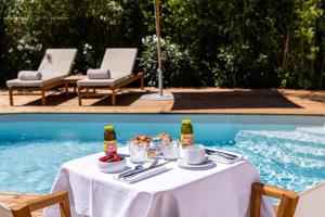 een tafel met eten en drinken naast een zwembad bij Le clos de la pinède chambre Deluxe 300 e par chambre in Saint-Tropez