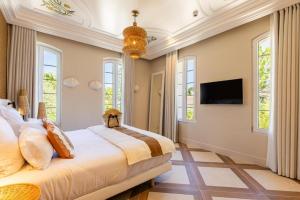 een slaapkamer met een bed, een tv en ramen bij Le clos de la pinède chambre Deluxe 300 e par chambre in Saint-Tropez