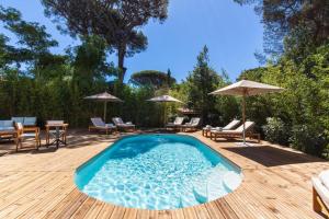 een zwembad op een houten terras met stoelen en parasols bij Le clos de la pinède chambre Deluxe 300 e par chambre in Saint-Tropez