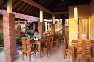 a man sitting at a table in a restaurant at Petit Boo Amed in Amed