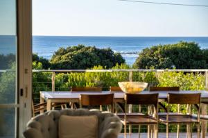a table and chairs on a balcony with the ocean at Percy Street I Private Properties in Gracetown