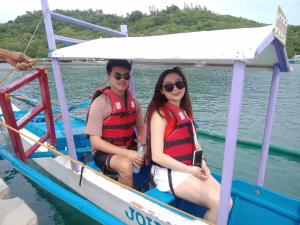 two people sitting on a boat in the water at Villa Monica Hotel in Balatero
