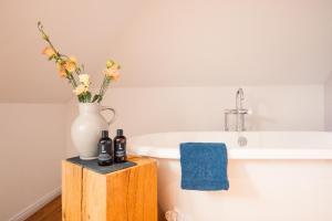 a bathroom with a white vase and a bath tub at Libertine Lindenberg in Frankfurt/Main