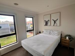 a bedroom with a white bed and two windows at The Lakes Homestead - Shared House in Mill Park