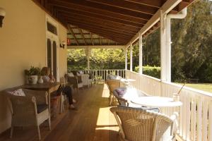 a porch with tables and chairs on a deck at The Carriages Boutique Hotel and Vineyard in Pokolbin